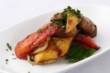 Iştah açıcı ızgara sebzeler - tatlı biber (kırmızı biber) - mantar ve yeşillik ile kırmızı ve sarı. Beyaz bir tabakta. Güzel servis