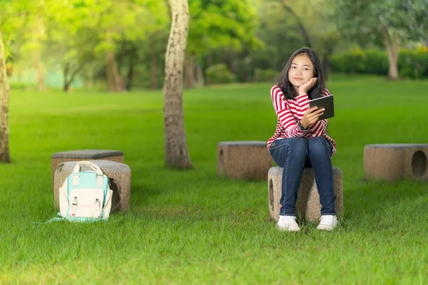 在阳光明媚的夏日 学校公园里有一个数码平板电脑的亚洲学生女孩 — 图库照片