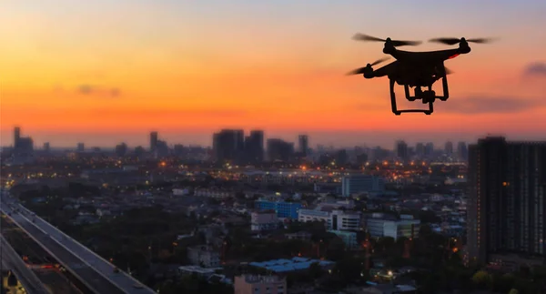 Silueta de dron volando sobre la ciudad al atardecer — Foto de Stock