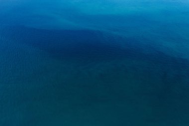 Mavi okyanus yüzeyinin arka planda havadan görünümü