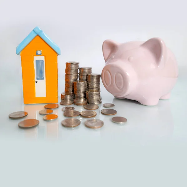 Piggy bank with small house and coin on white background