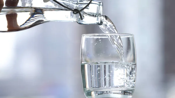 Пейте воду, наливая в стекло на стол — стоковое фото