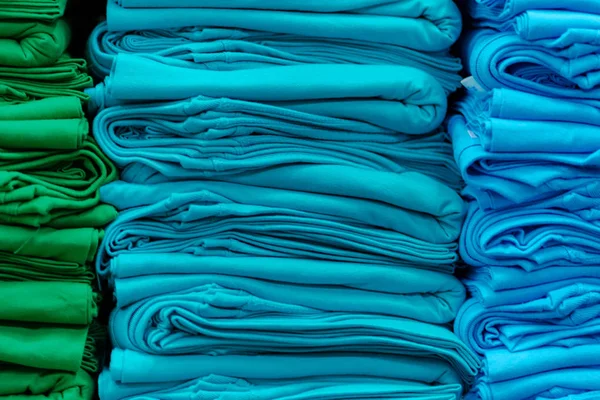 Raflara yığılmış renkli tişörtlerin yakın çekim — Stok fotoğraf