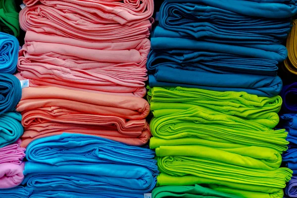 Close up de t-shirts coloridas empilhadas nas prateleiras — Fotografia de Stock