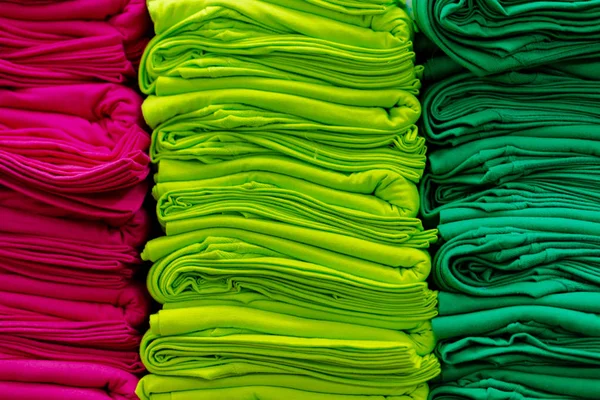 Close up de t-shirts coloridas empilhadas nas prateleiras — Fotografia de Stock