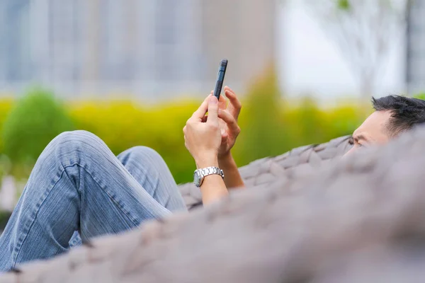 Man relaxing and using smartphone in city park — Stock Photo, Image