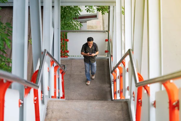 街中で階段を上り、スマートフォンを使う男 — ストック写真