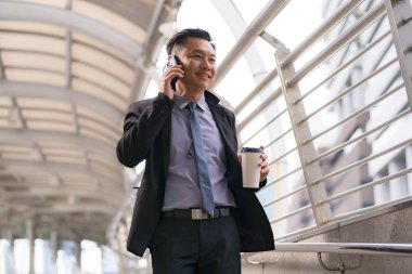 Asyalı İşadamı yürüyüş ve busin ile cep telefonu konuşuyor