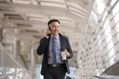 Asyalı İşadamı yürüyüş ve busin ile cep telefonu konuşuyor