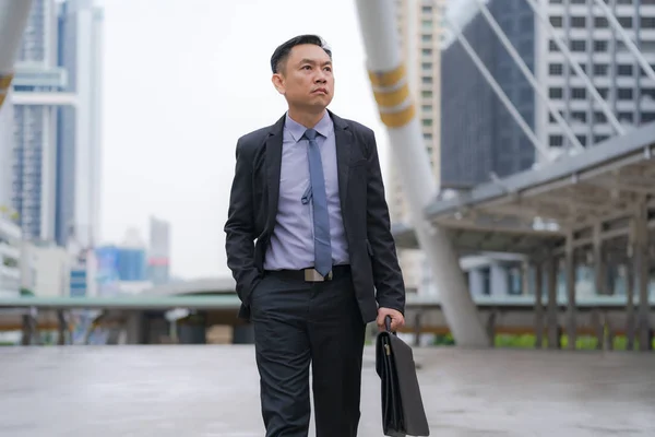 Azjatycki biznesmen chodzenie i trzymanie Aktówka z biznesem — Zdjęcie stockowe