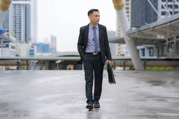 Azjatycki biznesmen chodzenie i trzymanie Aktówka z biznesem — Zdjęcie stockowe