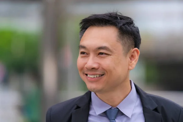 Asiatico uomo d'affari in piedi e sorridente con ufficio buil — Foto Stock
