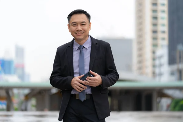 Asiatico imprenditore standing and holding cellulare con busines — Foto Stock