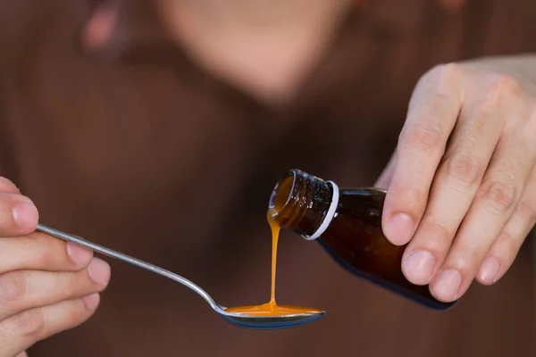 Man hand gieten medicatie of antipyretische siroop van fles naar — Stockfoto