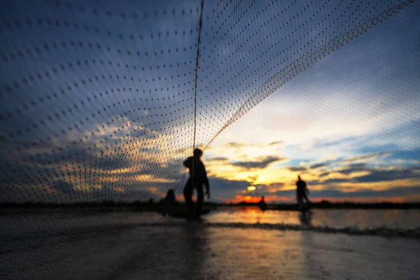 Silhouette of Fisherman on fishing boat with net on the lake at — Stock Photo, Image