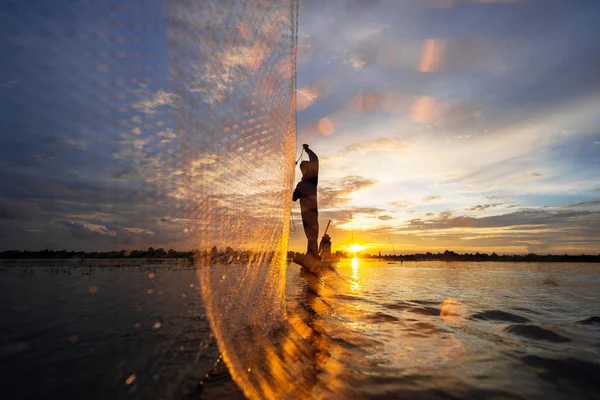 Silhouette of Fisherman on fishing boat with net on the lake at — Stock Photo, Image