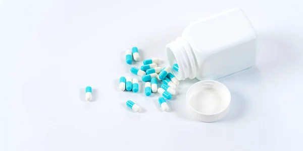Blue and white capsules pills pouring from the bottle on white b — Stock Photo, Image