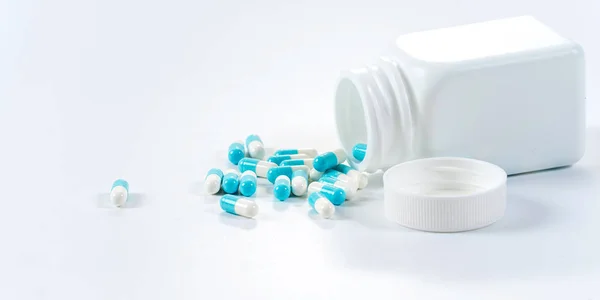 Blue and white capsules pills pouring from the bottle on white b — Stock Photo, Image