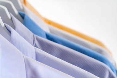 Erkeklerin gömleklerini kapatın, beyaz arka planda askılarda giysiler