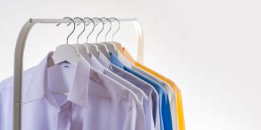 Erkeklerin gömleklerini kapatın, beyaz arka planda askılarda giysiler