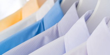 Erkeklerin gömleklerini kapatın, beyaz arka planda askılarda giysiler