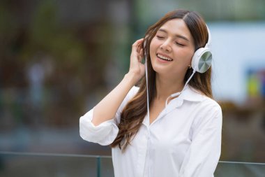 Genç ve güzel bir kadının portresi gülen yüzlü, açık havada müziğin tadını çıkarıyor.