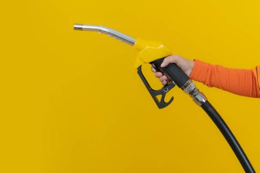 Kadın yakıt hortumunu sarı arkaplanda izole etmiş.