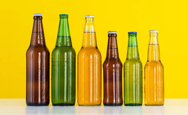 Group of Six bottles of beer on a yellow background, Close up