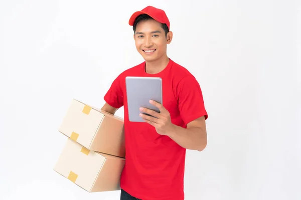 Smiling delivery man employee in red cap blank t-shirt uniform standing with parcel post box isolated on white background