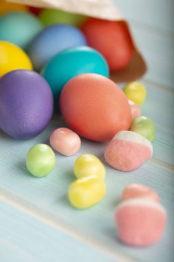 Bir kağıt torba ve tatlılar bir mavi ahşap tablo Easter renkli boyalı tavuk yumurtası