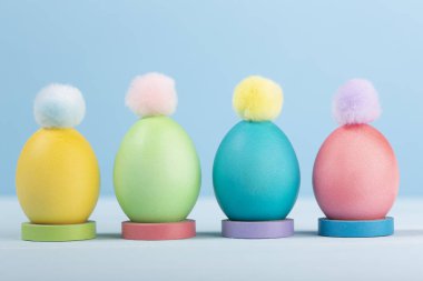 Boyalı parlak Paskalya yumurtaları standları ile mavi bir arka plan üzerinde renkli çiçekler.