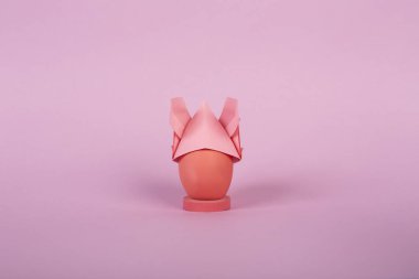 Mutlu Paskalya tatil kavramı kopya alanı ile pembe Kağıt arka plan üzerinde kulakları ile bir tavşan origami şapka boyalı tavuk yumurtası.