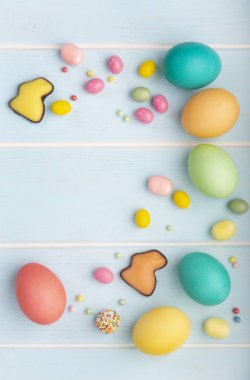 Paskalya renkli tavuk yumurta, çikolata bunnies, tatlılar ve ahşap mavi arka plan üzerinde renkli sprinkles çeşitli