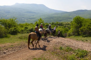Alushta, Kırım yakınlarındaki Hayalet vadisi etrafında atlar üzerinde dağ binicilik gezisi turist grubu.