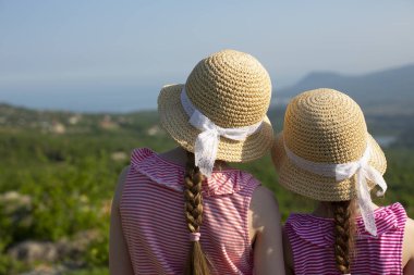 Dantel kurdeleler ile güzel yaz saman kapaklar iki küçük sevimli kız arka görünümü birlikte duruyor ve Ghost vadisi ve Karadeniz, Kırım yakınındaki dağlarda güzel manzara bakıyor.