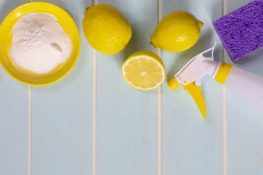 Eko temizlik için doğal ürünler. Eko temizlik için limon, kabartma tozu ve sirke. Sarı ve mor nesneler. Mavi ahşap arka plan.