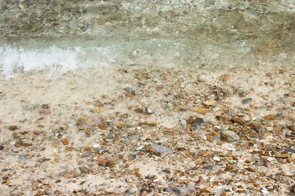 Ondas suaves con espuma de agua en guijarros y playa de arena . —  Fotos de Stock
