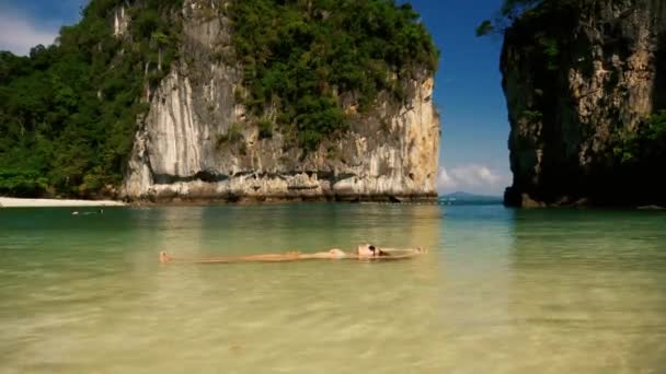 Menina bonita flutuando na água em uma praia tropical — Vídeo de Stock