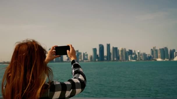 Jente som tar bilder til skyskrapere med smarttelefon i Doha qatar – stockvideo