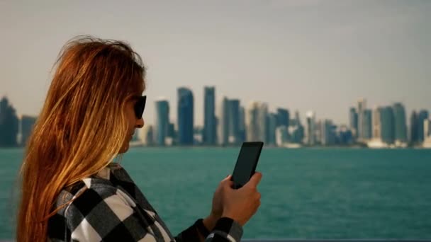 Chica mensajes de texto en el teléfono inteligente con rascacielos en el fondo — Vídeo de stock