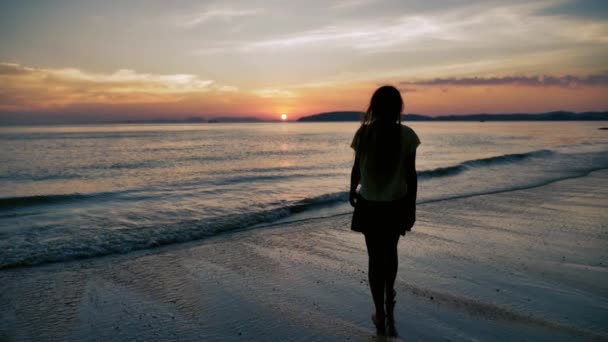 Jonge vrouw gaan in de zee in slow motion bij zonsondergang op een tropisch strand — Stockvideo