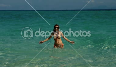 Mutlu kız açık mavi su dalgaları yavaş hareket oynarken