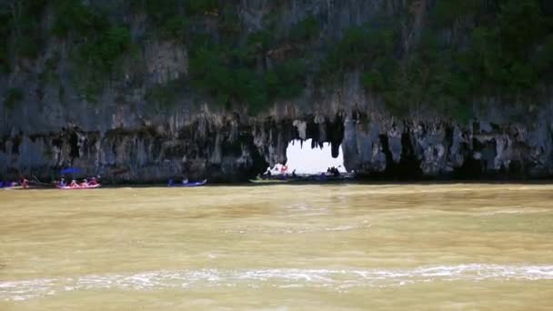 Les gens faisant du kayak près du rivage rocheux et des grottes — Video