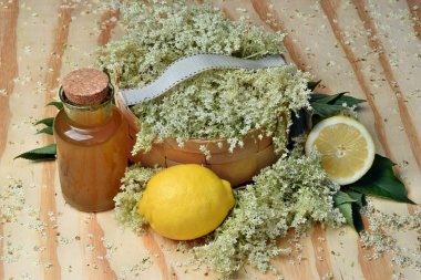 Ahşap zemin üzerinde limon ve taze çiçek olan mürver çiçeği şurubu.