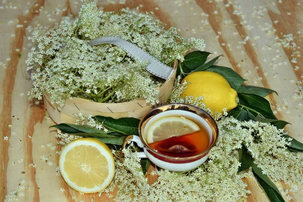 接骨糖浆在木质背景和鲜花上的茶 — 图库照片