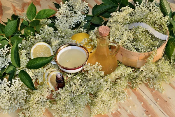Elderflower şurubu, ahşap arka planda yağ ve taze çiçek.