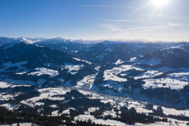Bir dron görünümünden bir kışın orman ve Alpler ve küçük köylerde kar ile kaplı dağlar