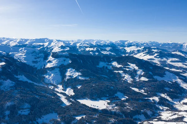 Яскрава панорама гірських хребтів зі снігом і льодом на вершинах на тлі блакитного неба взимку і щільних лісів — стокове фото