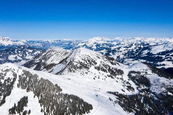 Brillante panorama de cadenas montañosas con nieve y hielo en las cimas contra el cielo azul en invierno y bosques densos —  Fotos de Stock