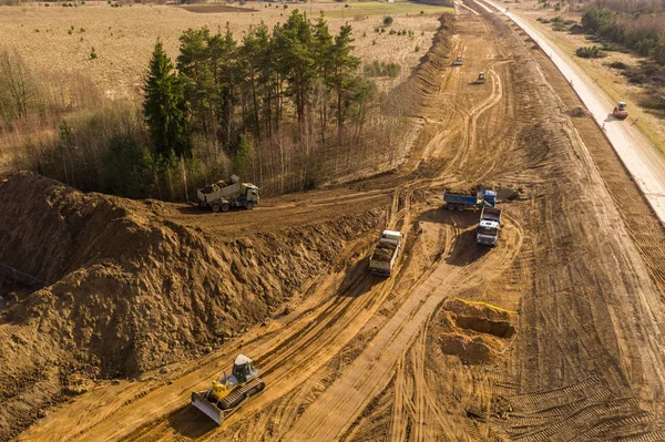 Drone view of trucks, bulldozer and road repair work in rural landscape.